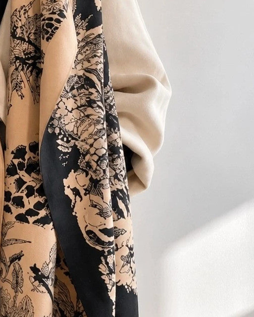 Beige shawl with black floral pattern, soft polyester material, versatile design.