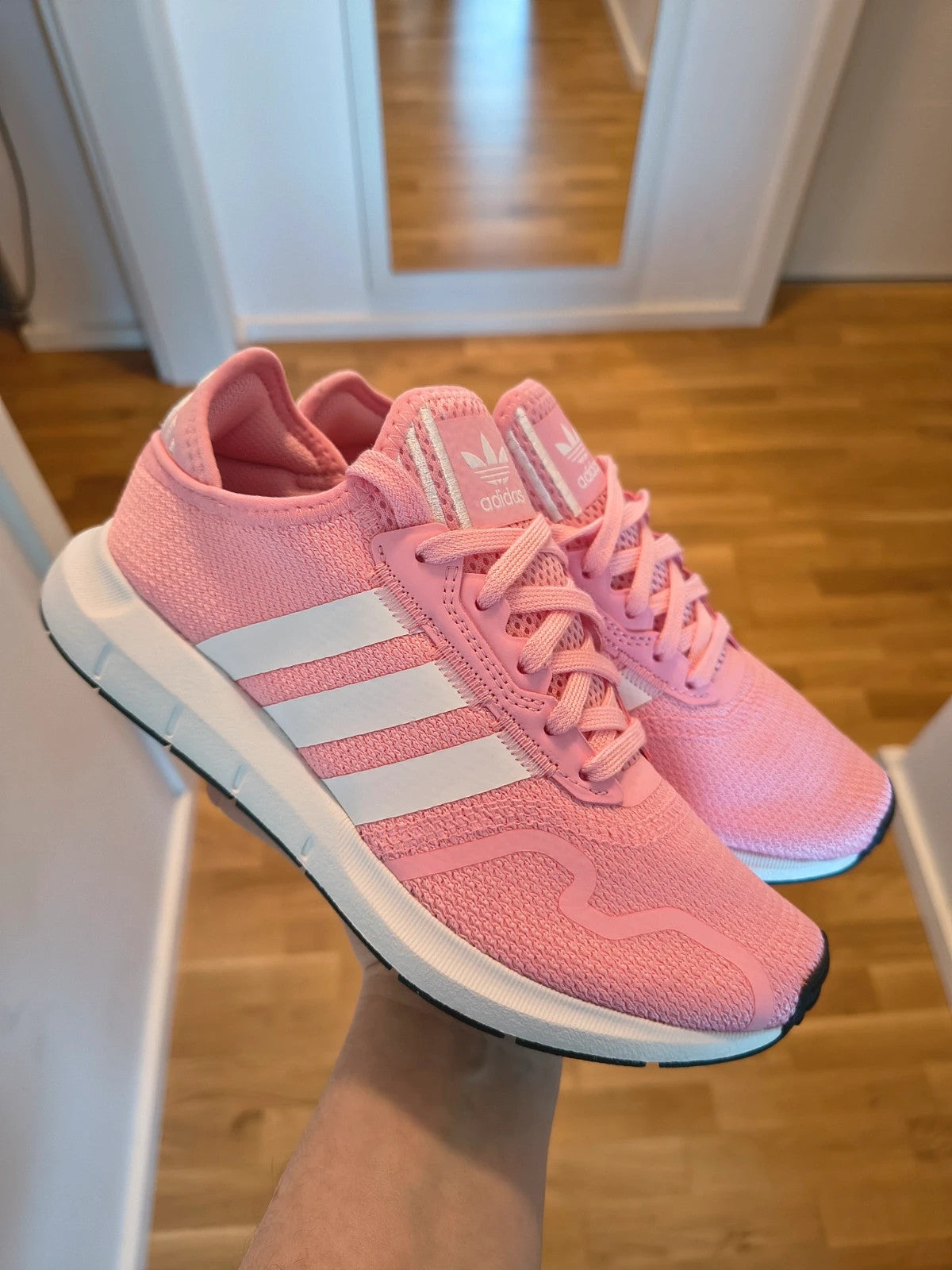 Adidas pink and white trainers with synthetic and textile materials, featuring slip-on and lace-up design.