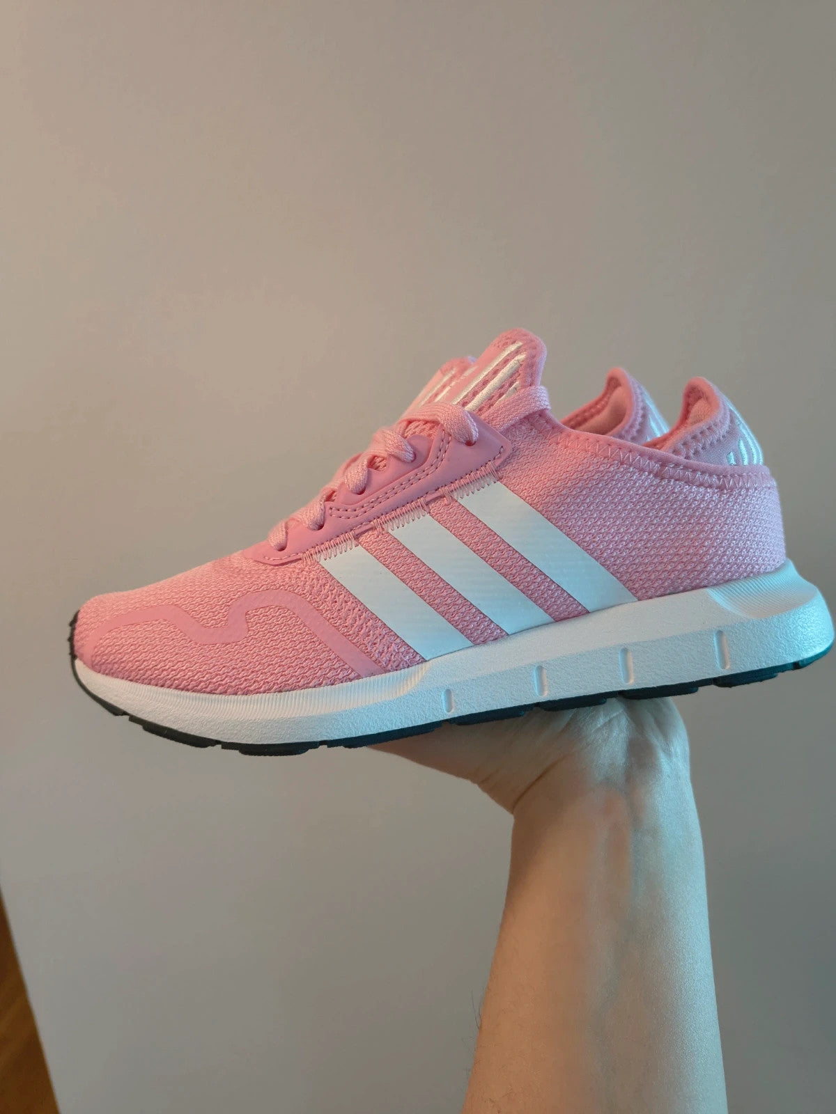 Adidas pink and white trainers with synthetic and textile materials, featuring slip-on and lace-up design.