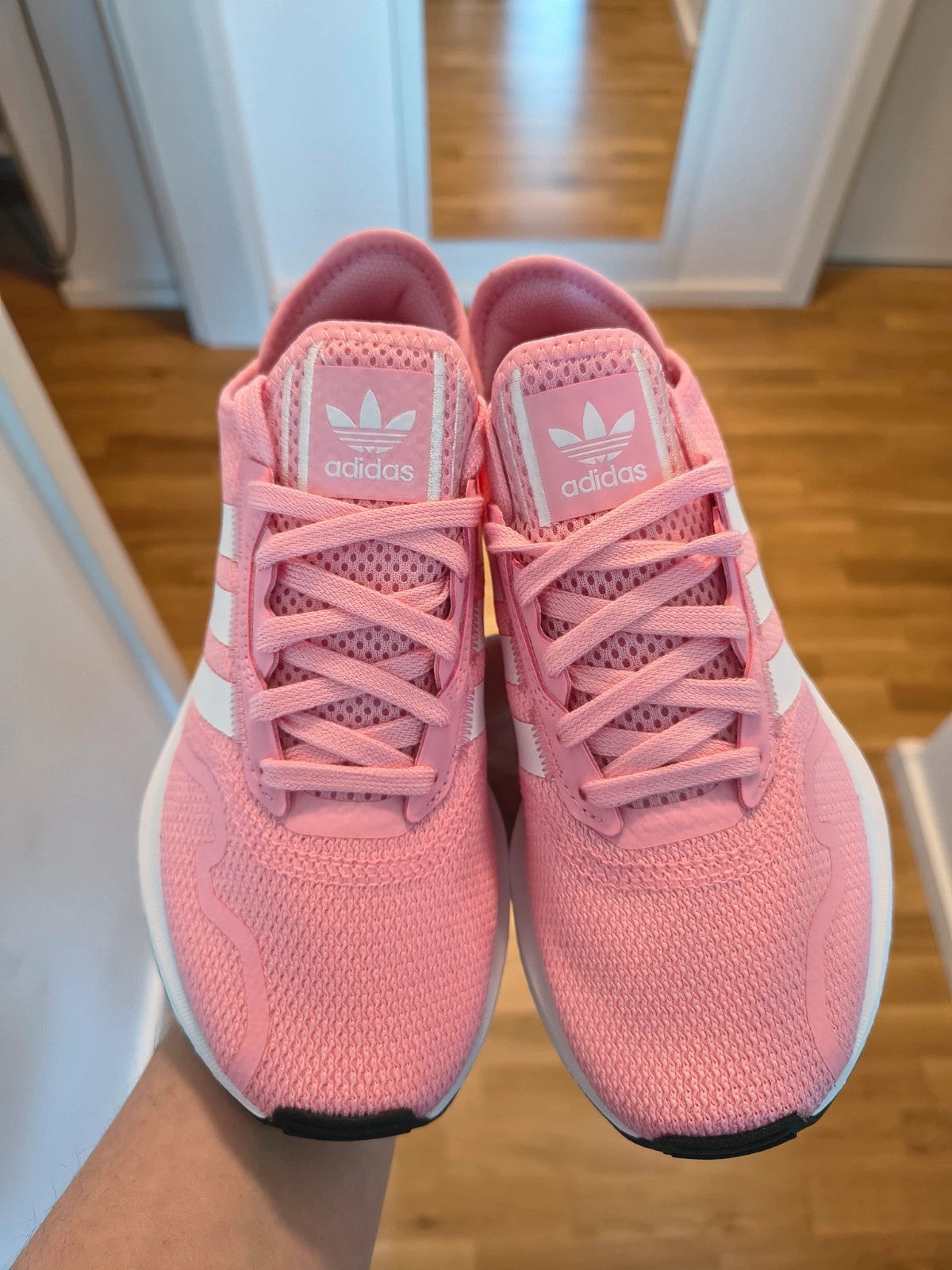 Adidas pink and white trainers with synthetic and textile materials, featuring slip-on and lace-up design.