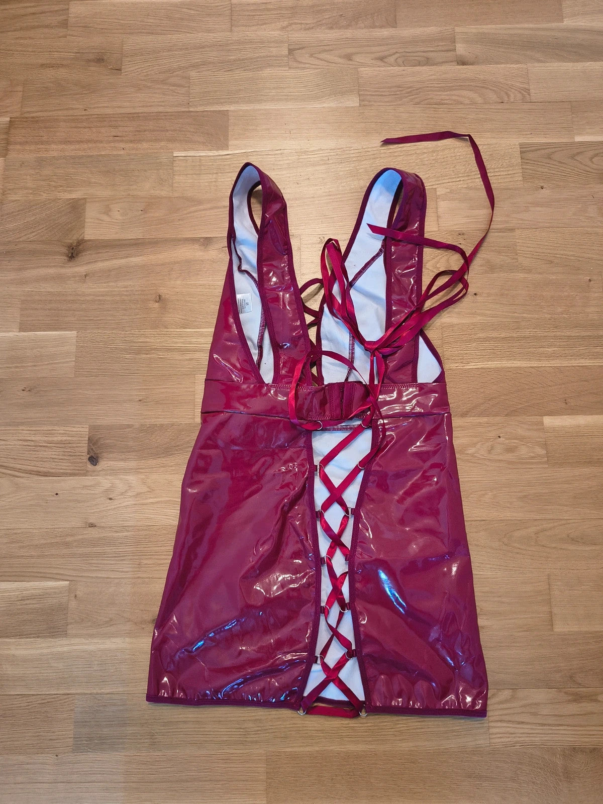 Bordeaux burgundy bandage dress with lace-up detail and glossy vinyl appearance.
