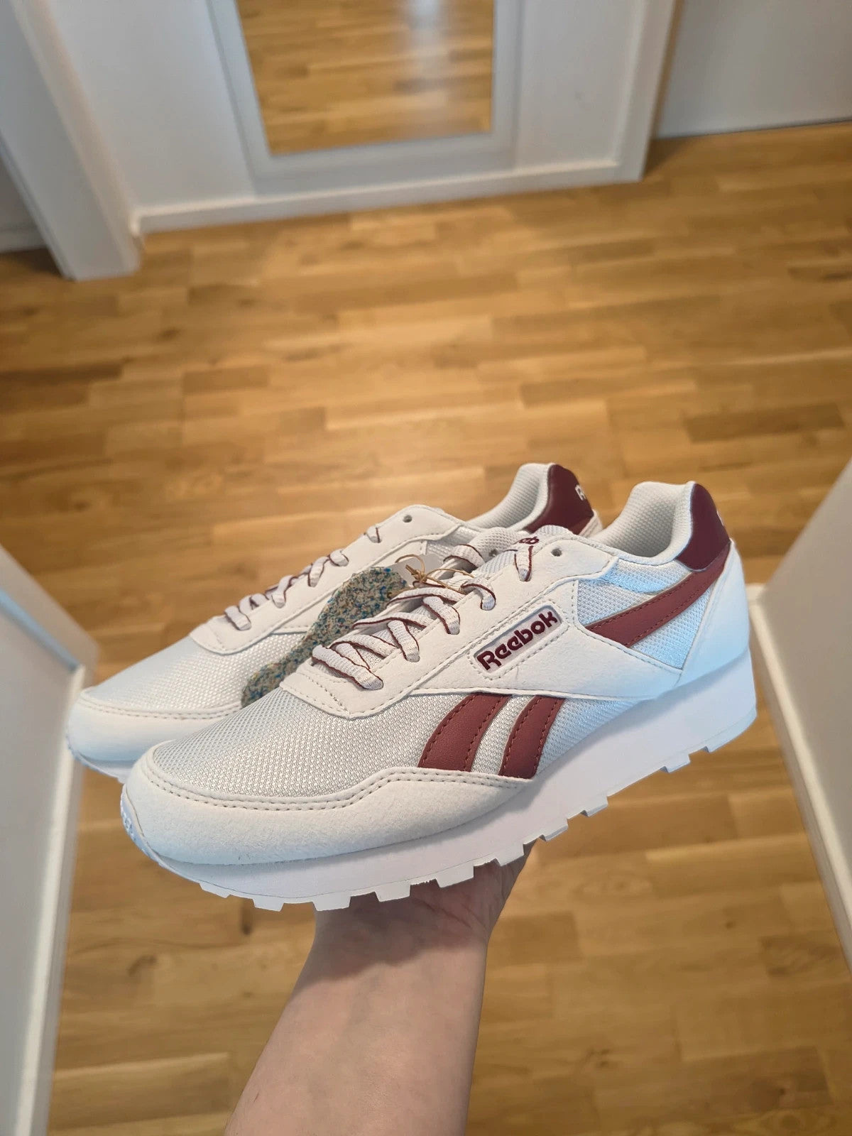 Reebok white trainers with synthetic and textile materials, featuring classic design elements.