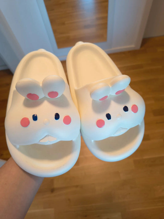 Slipper cream slides synthetic material with cartoon comic design and lightweight construction.