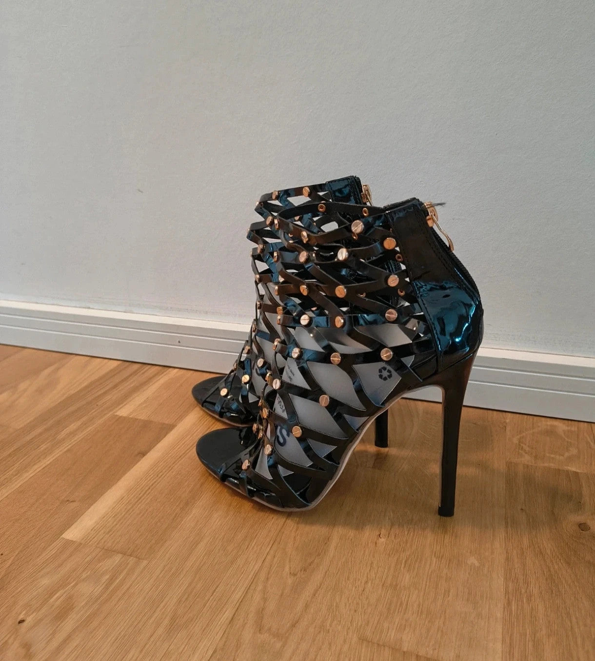 REI black high-heel sandals in patent finish with gold studs and open toe design.