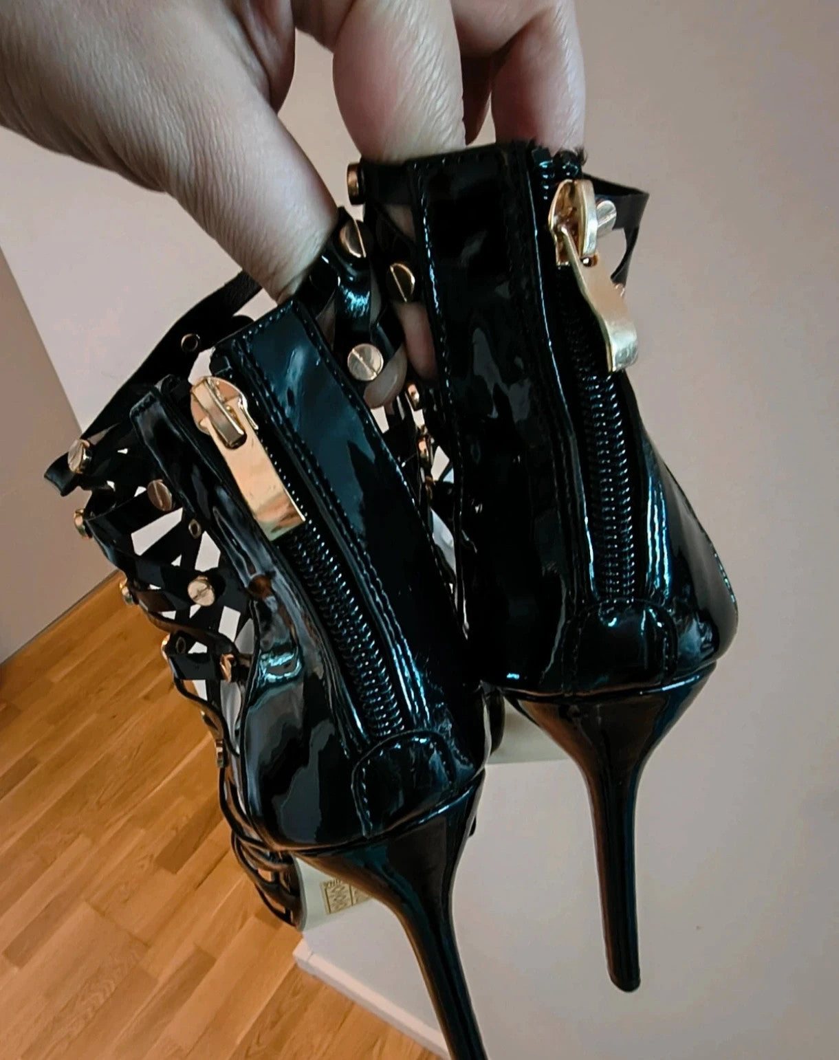 REI black high-heel sandals in patent finish with gold studs and open toe design.