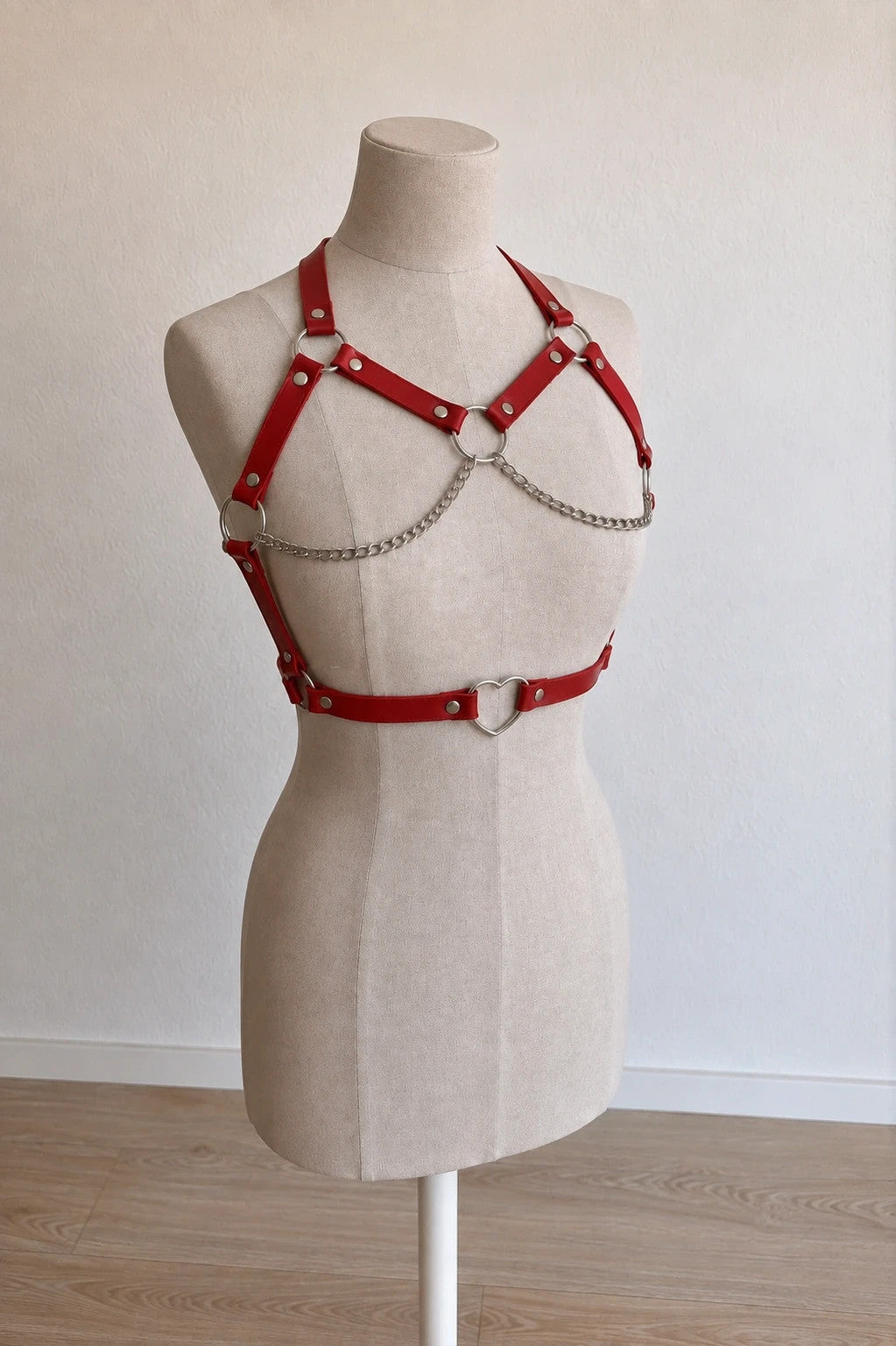 Outfit red body harness with silver metal rings, studs, and decorative chains.