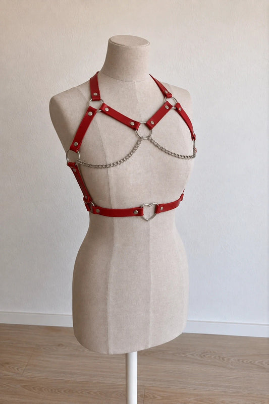 Outfit red body harness with silver metal rings, studs, and decorative chains.