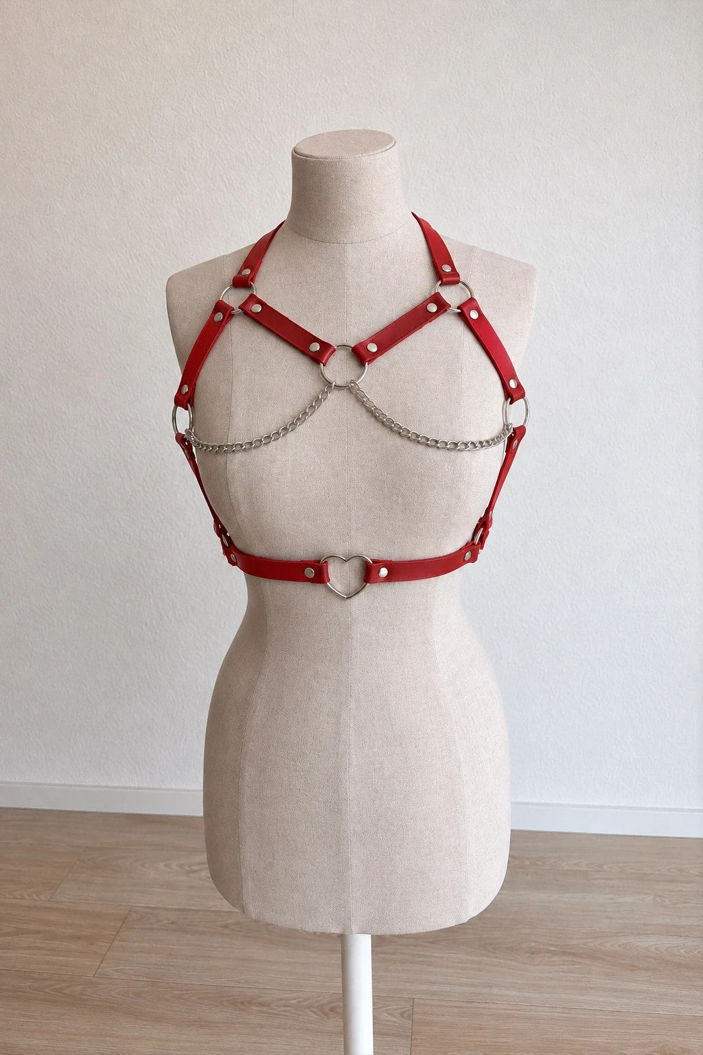 Outfit red body harness with silver metal rings, studs, and decorative chains.