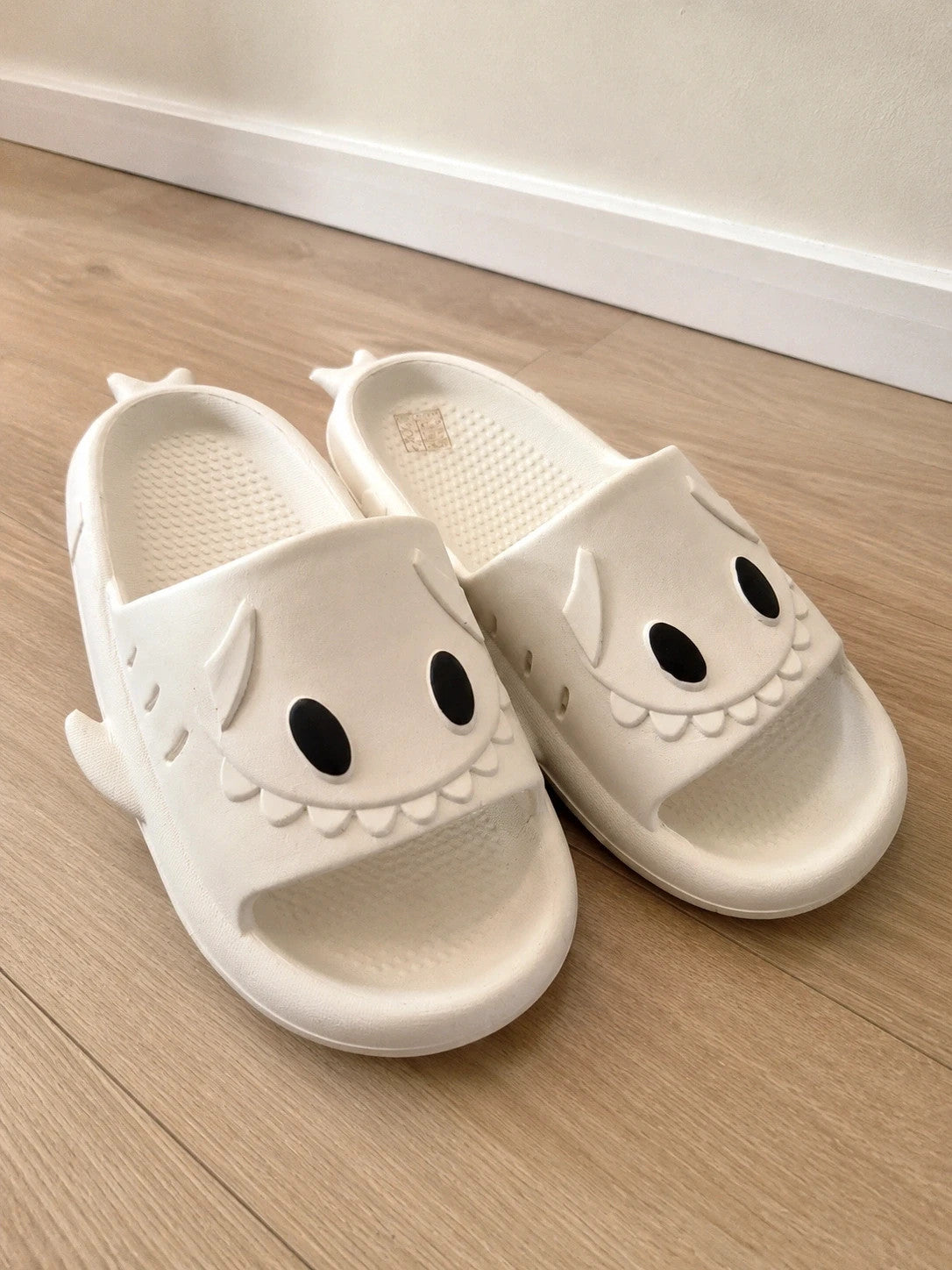 Perfekt cream slippers with monster design, featuring playful face and lightweight material.