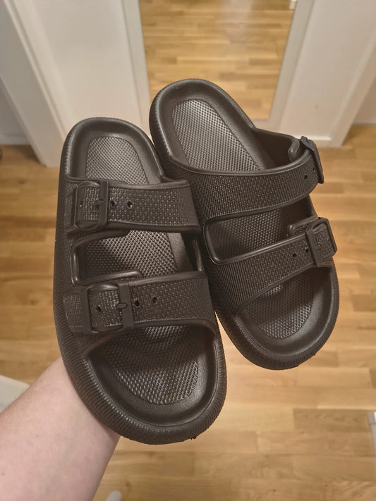 Schwarze Slipper mit zwei verstellbaren Schnallen, leichtes Synthetikmaterial, strukturierte Innensohle.