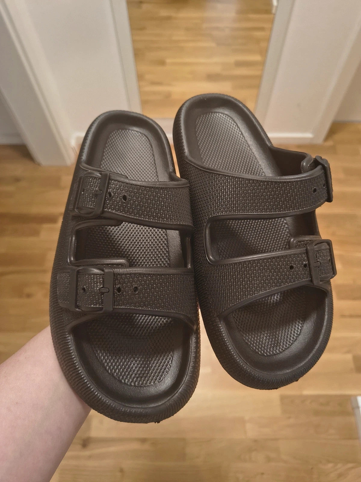 Schwarze Slipper mit zwei verstellbaren Schnallen, leichtes Synthetikmaterial, strukturierte Innensohle.