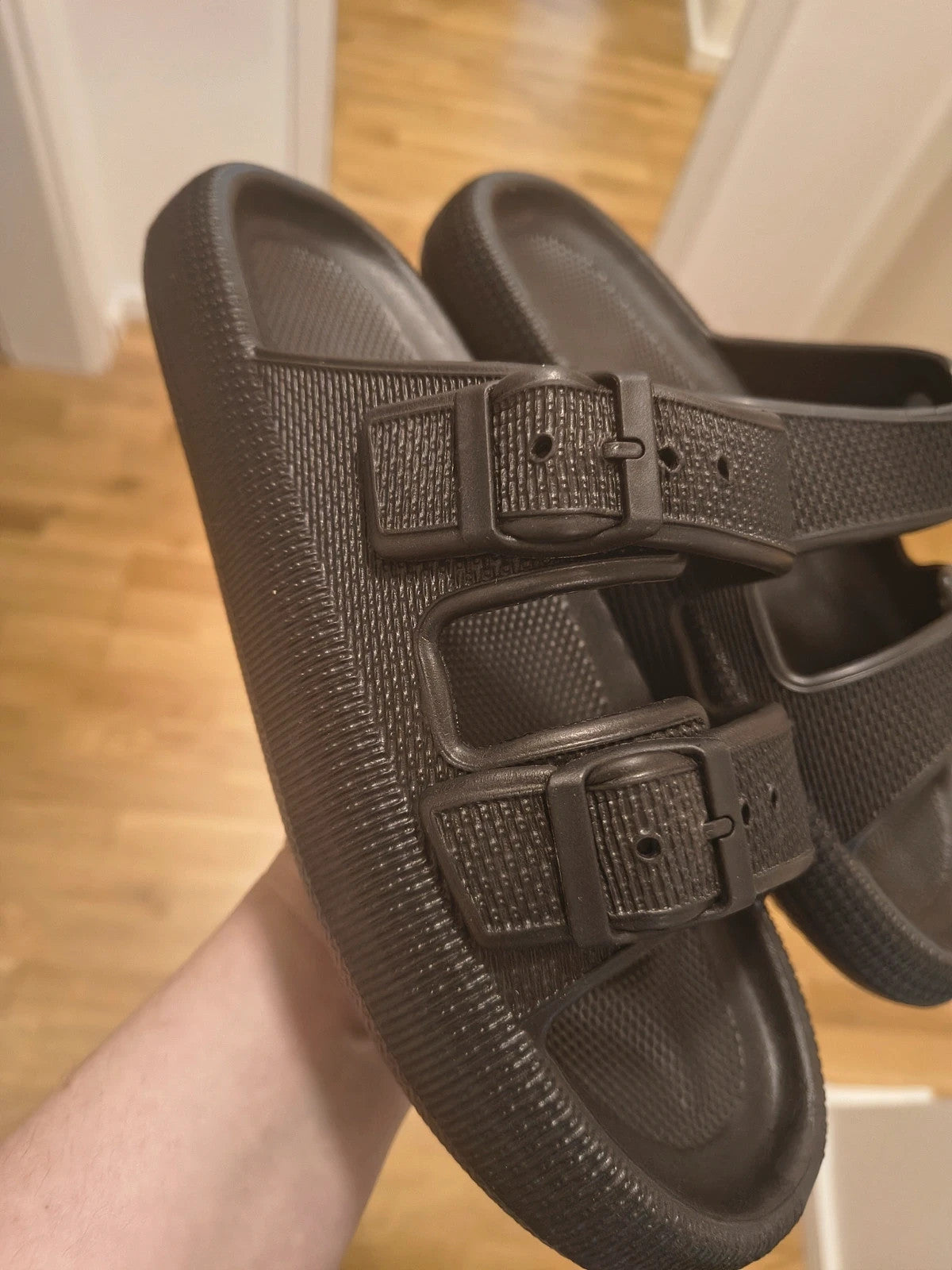 Schwarze Slipper mit zwei verstellbaren Schnallen, leichtes Synthetikmaterial, strukturierte Innensohle.