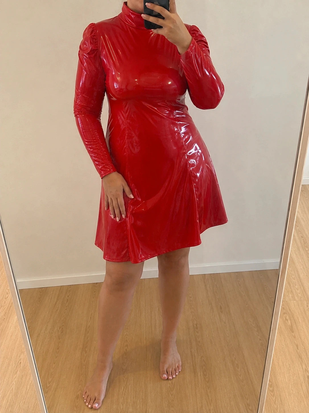 Red bandage dress with wetlook finish, standing collar, and long sleeves.