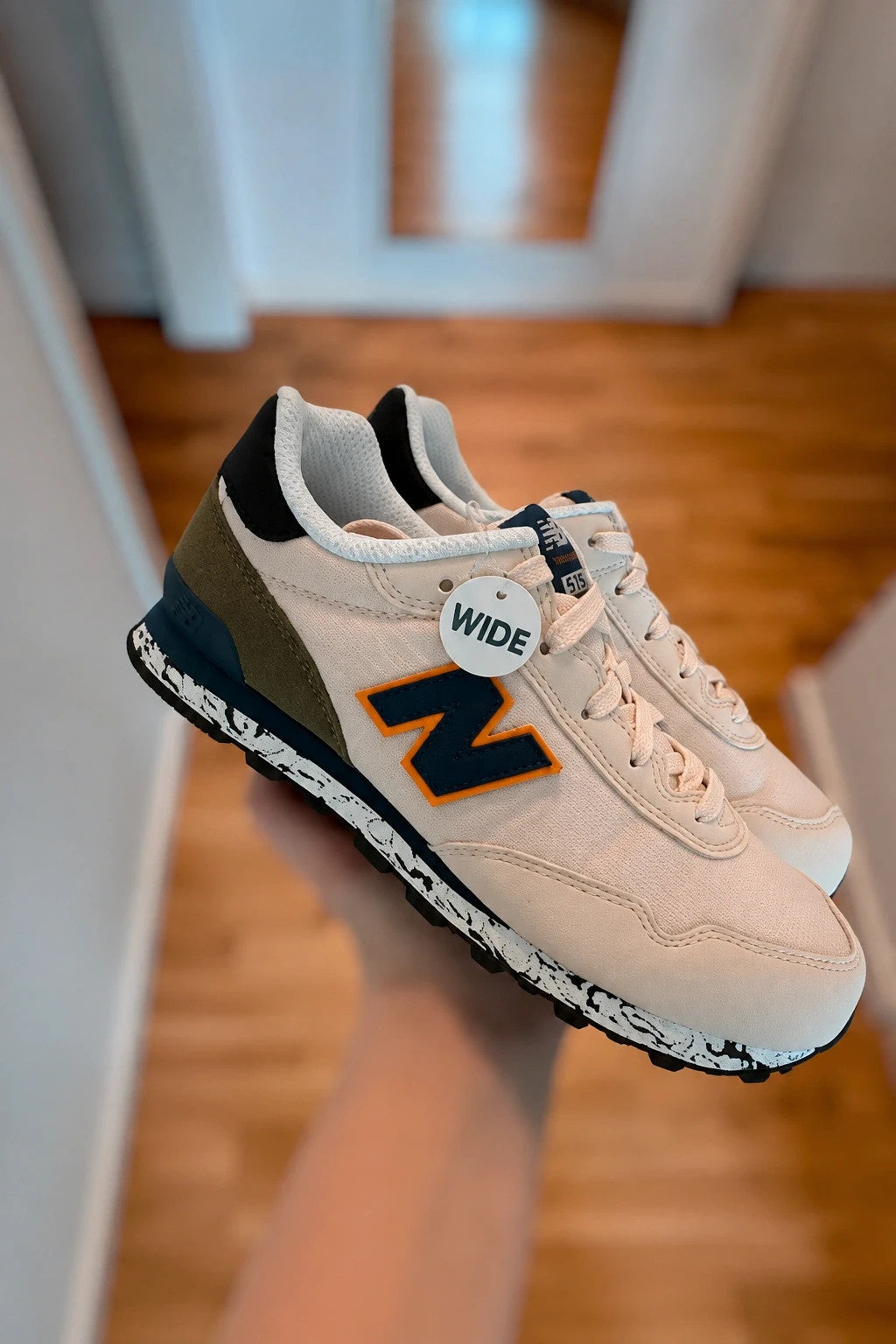 New Balance beige trainers with dark accents, textile and synthetic materials.