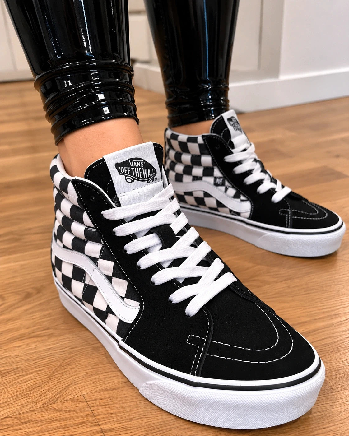 VANS black and white checkerboard high-top trainers with classic side stripe and leather material.