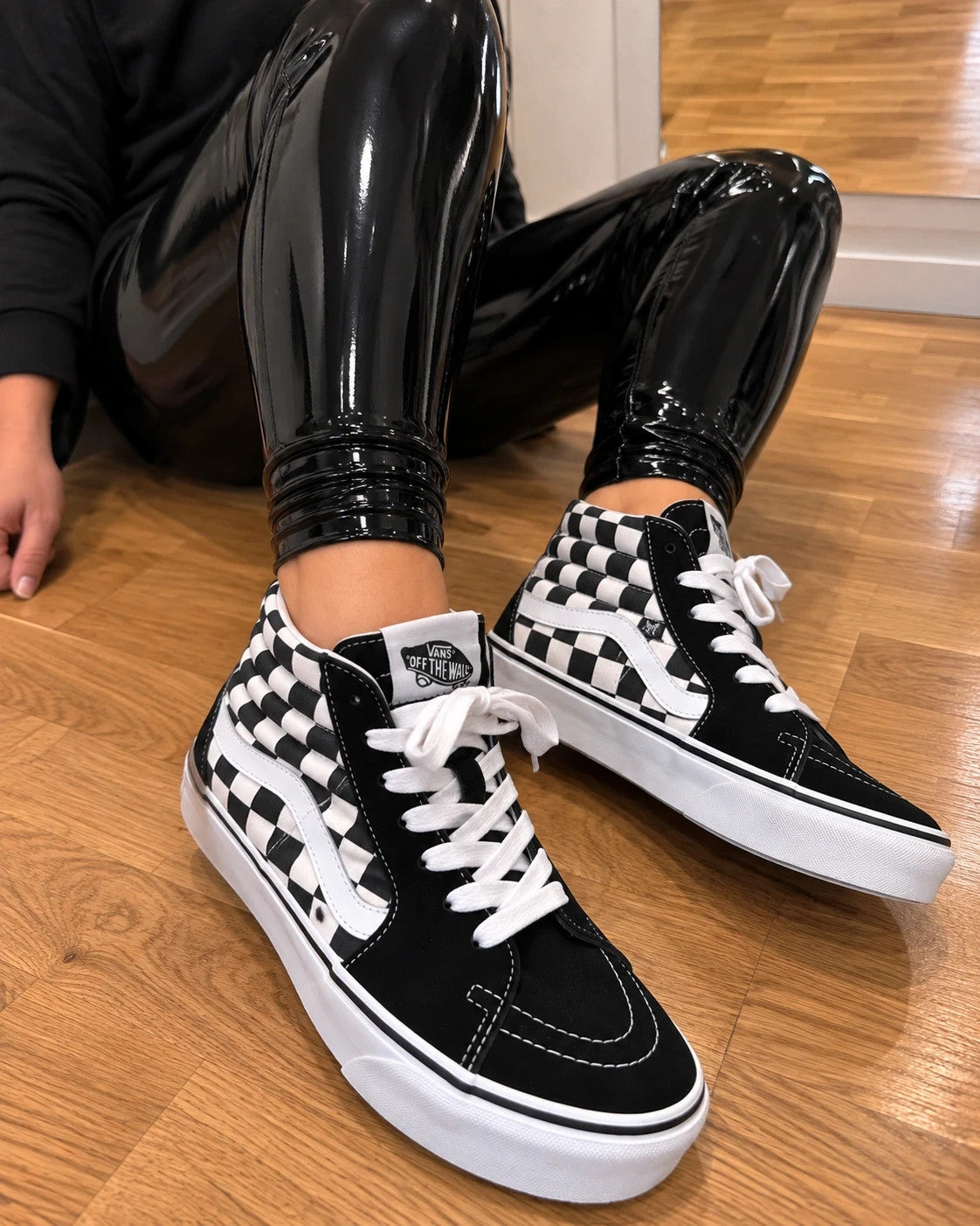 VANS black and white checkerboard high-top trainers with classic side stripe and leather material.