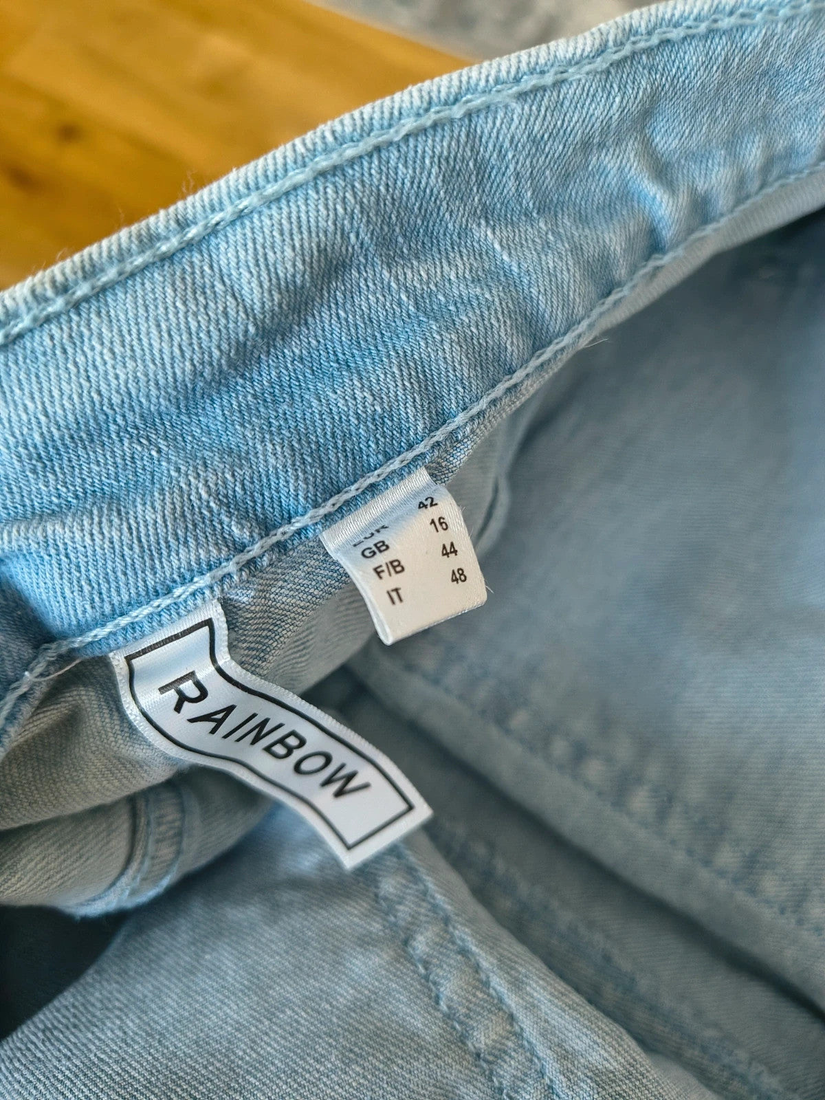 Rainbow blue straight jeans with unique overlapping waistband and two-button closure.