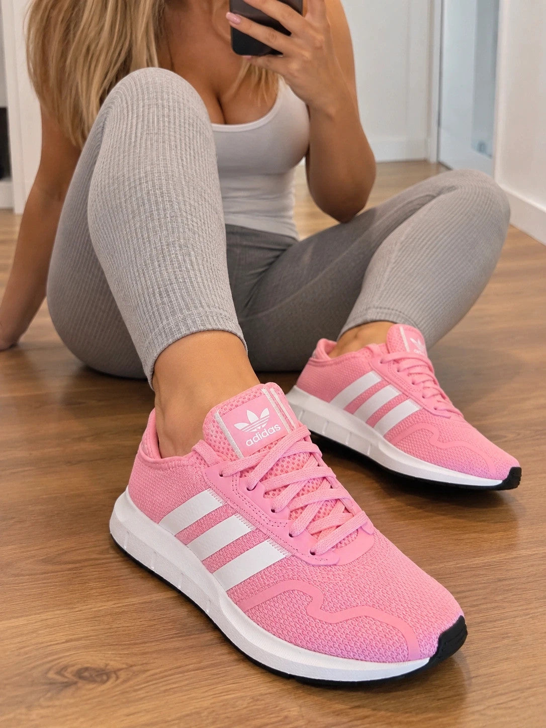 Adidas pink trainers with white stripes, breathable textile upper, and lace-up closure.