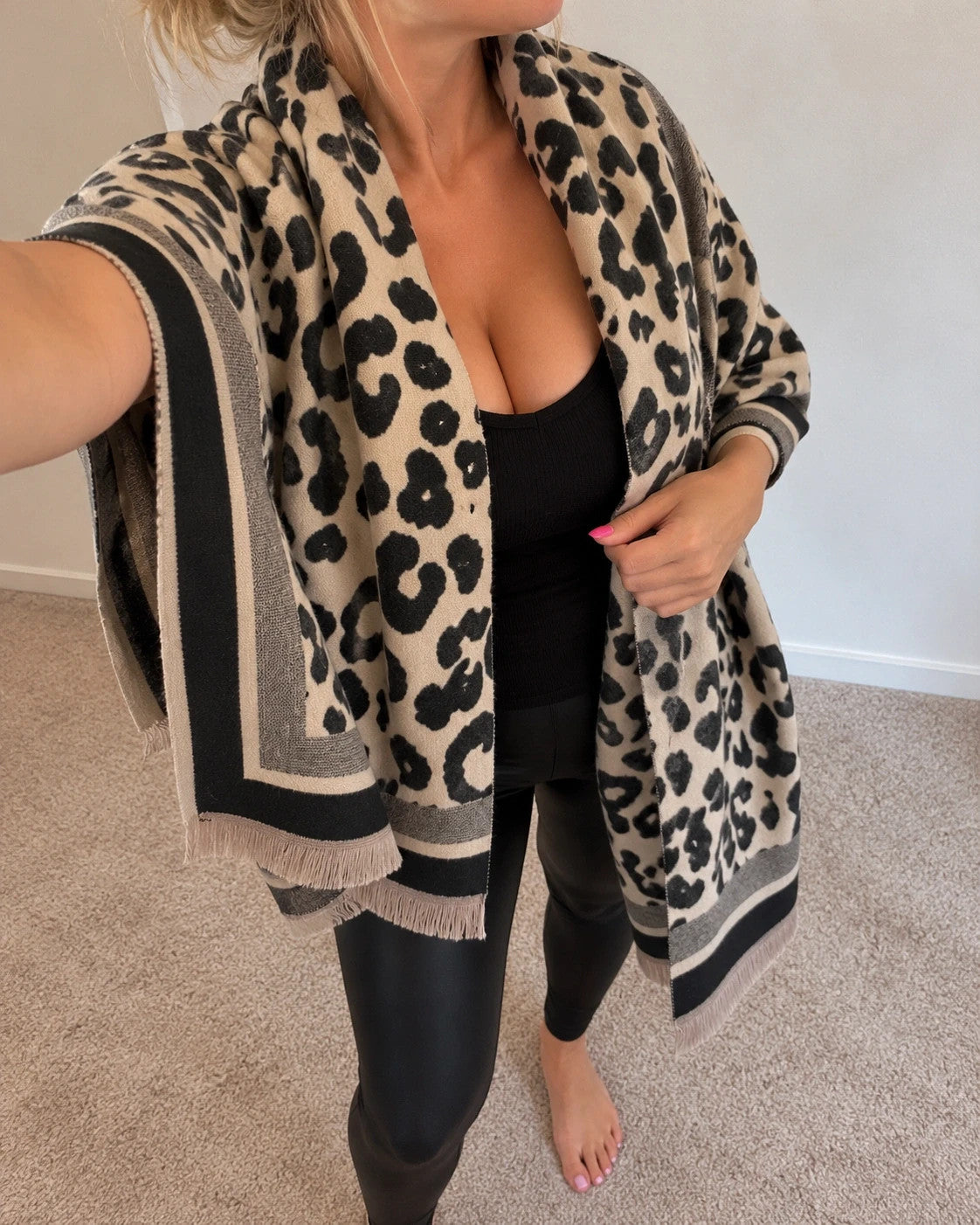 Beige scarf with black leopard print, fringed edges, reversible design, soft polyester material.