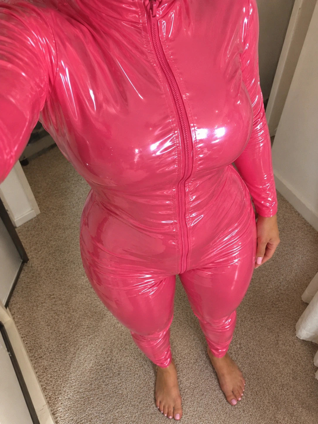 Pink jumpsuit with long sleeves and standing collar, figure-hugging fit.