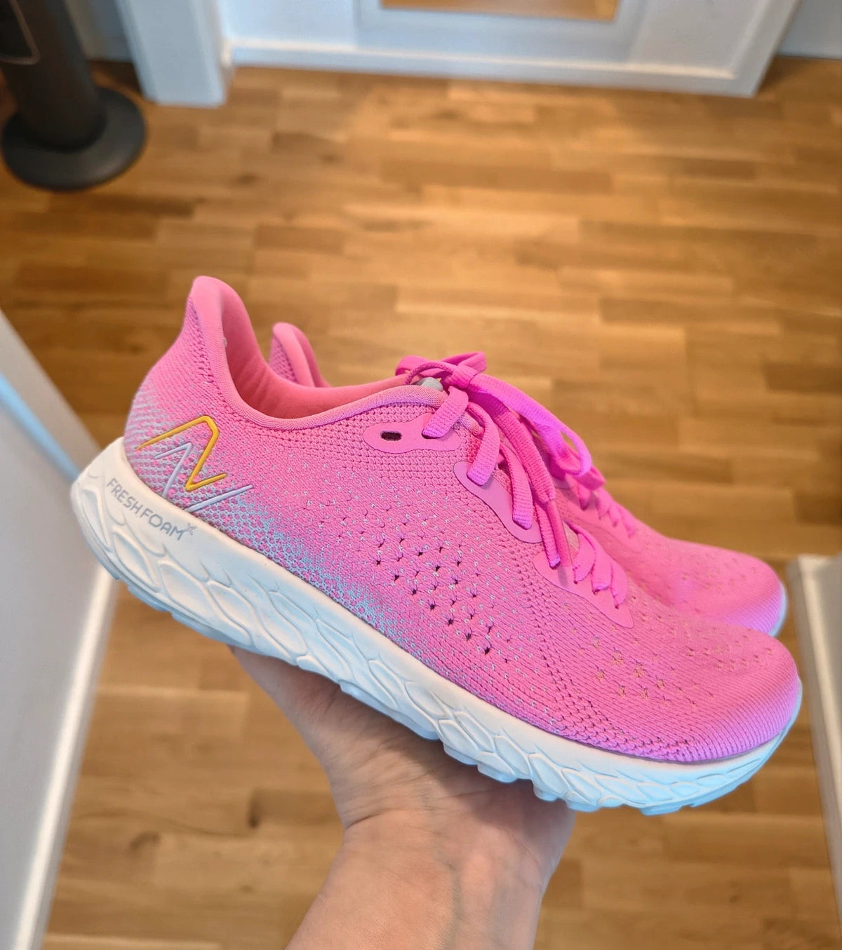 New Balance pink sneakers with white soles and contrasting logo, breathable textile material.