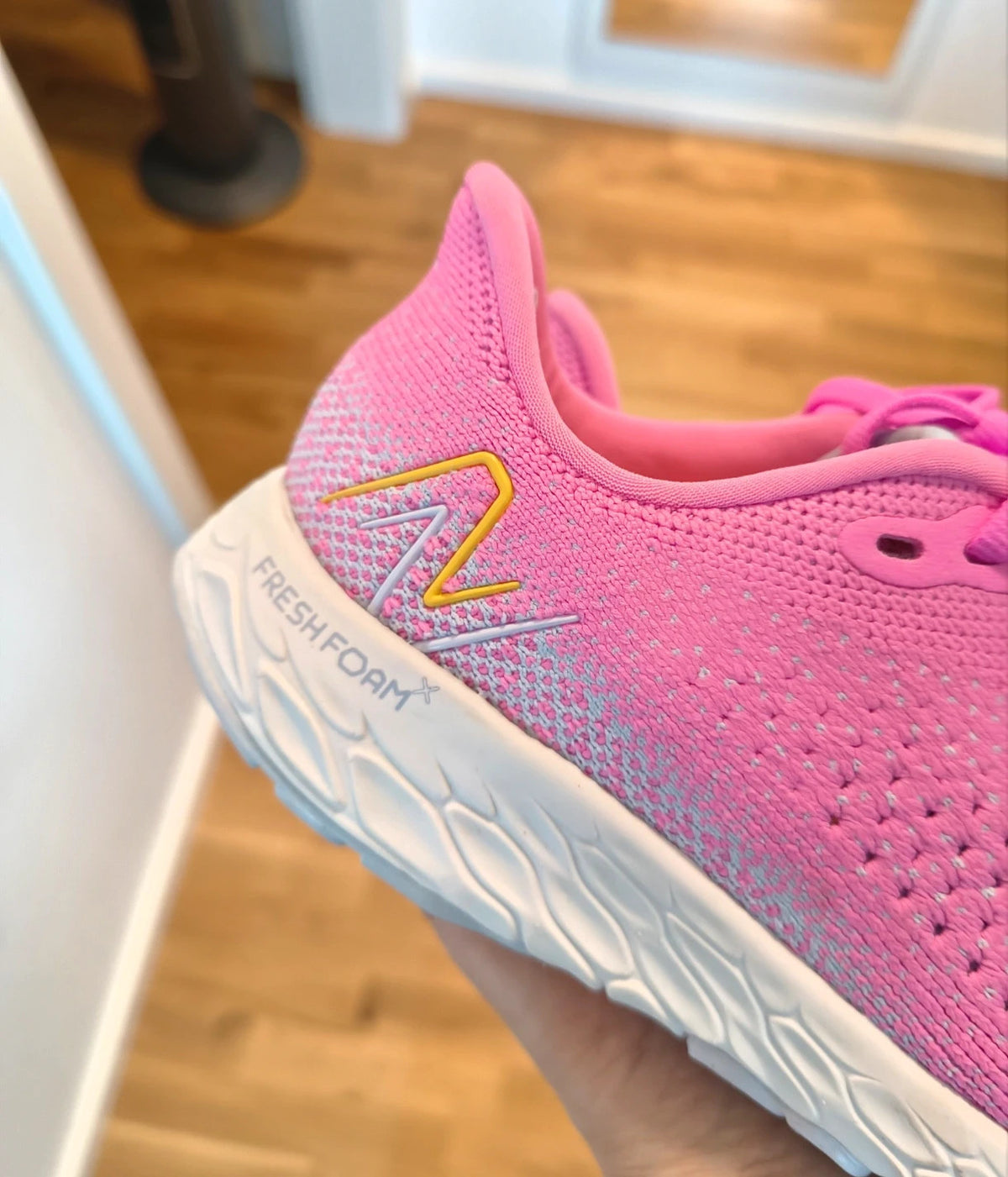 New Balance pink sneakers with white soles and contrasting logo, breathable textile material.