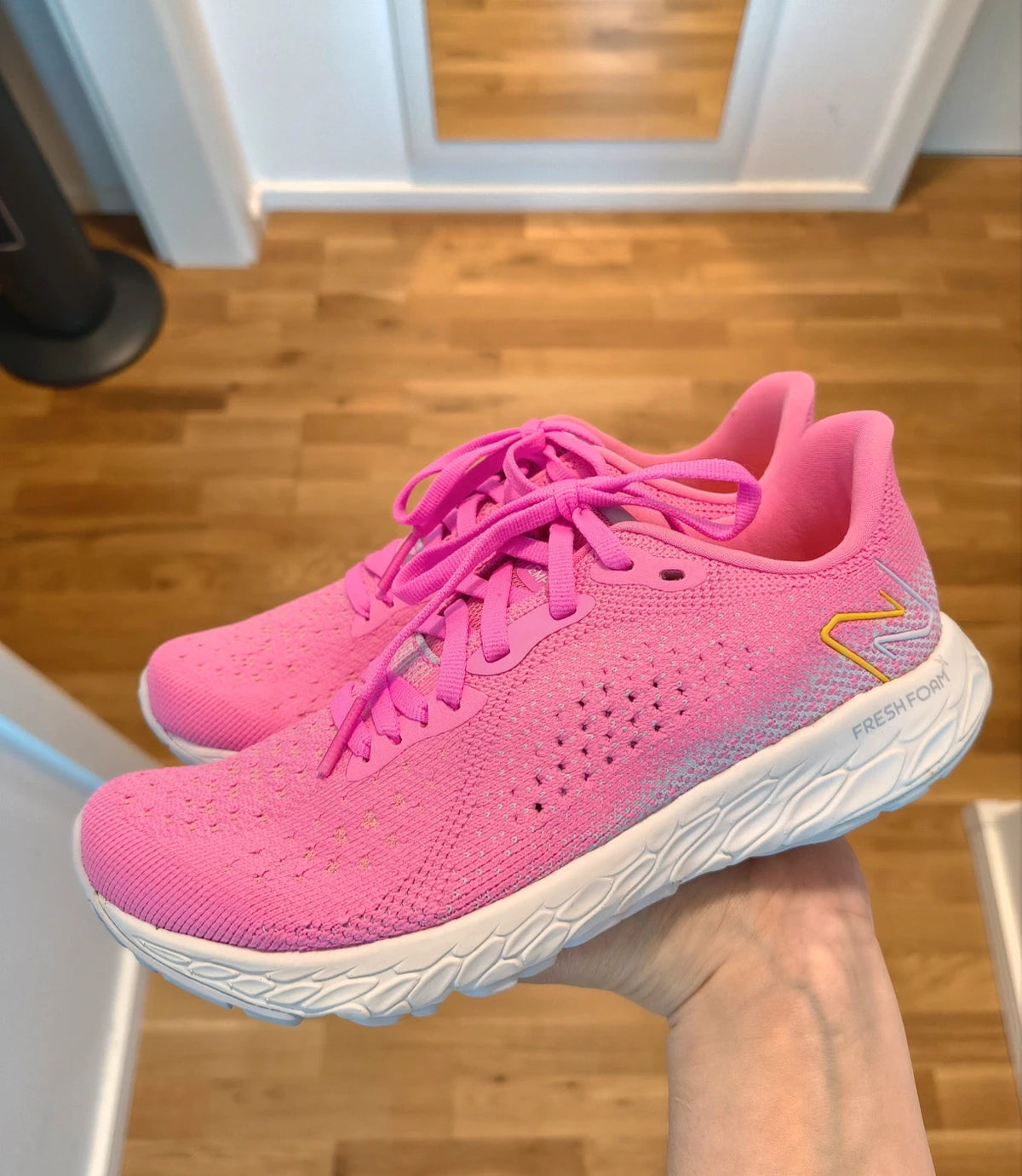 New Balance pink sneakers with white soles and contrasting logo, breathable textile material.