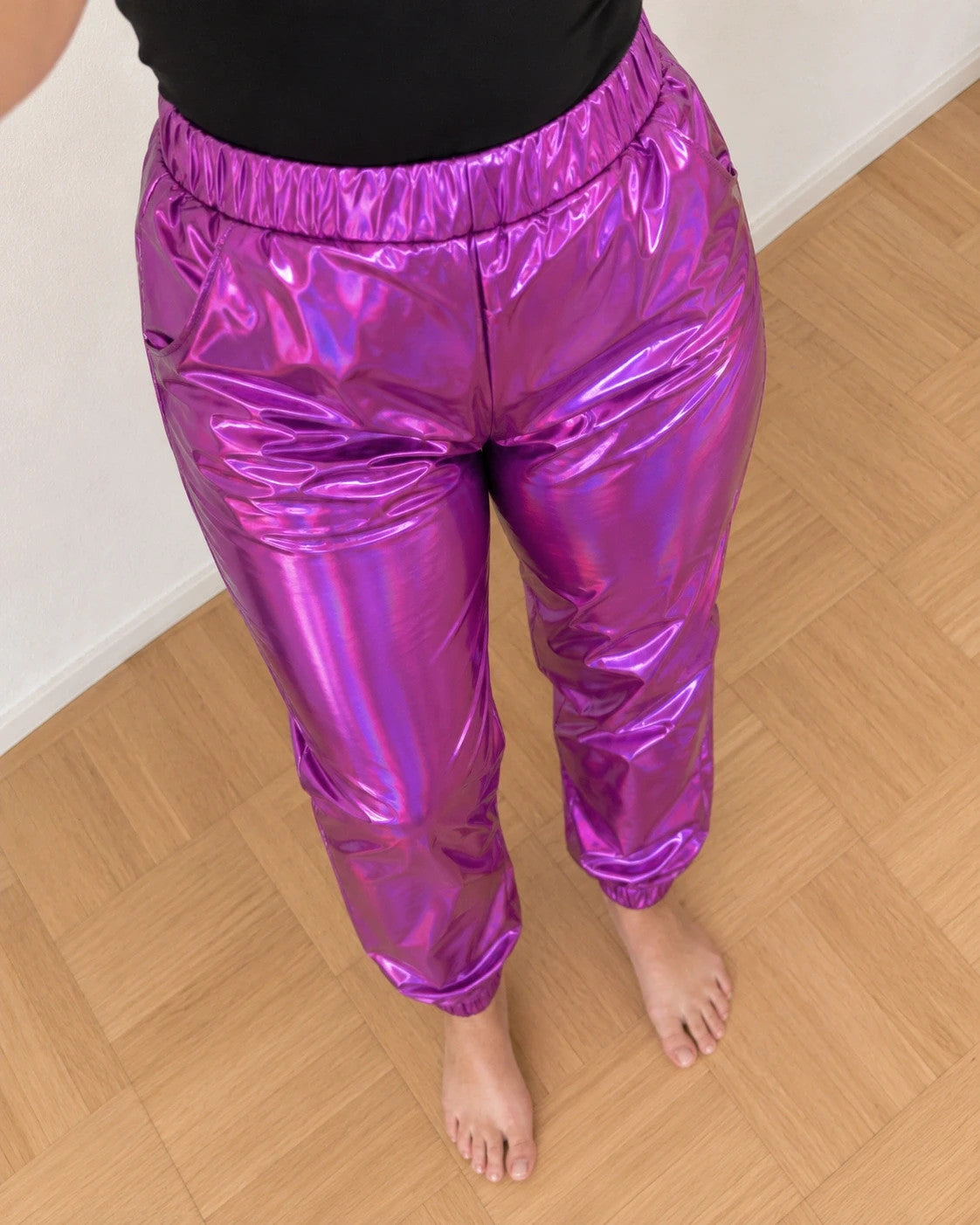 Lila purple jogging pants with shiny finish and fitted silhouette, featuring a smooth surface.