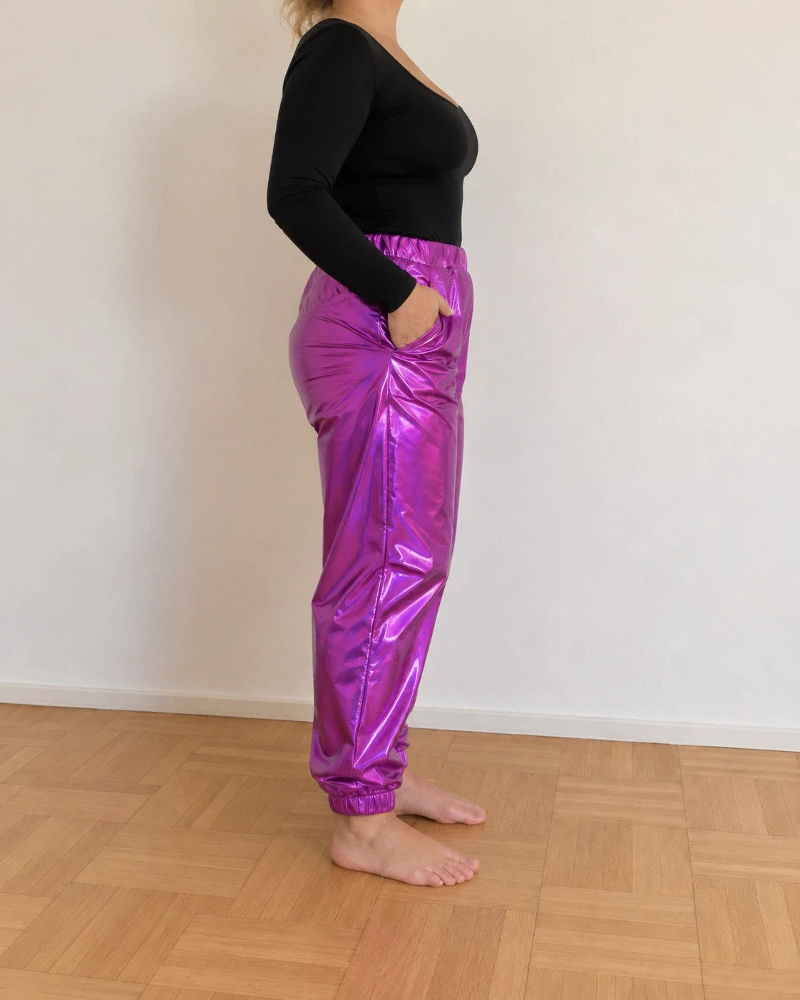 Lila purple jogging pants with shiny finish and fitted silhouette, featuring a smooth surface.