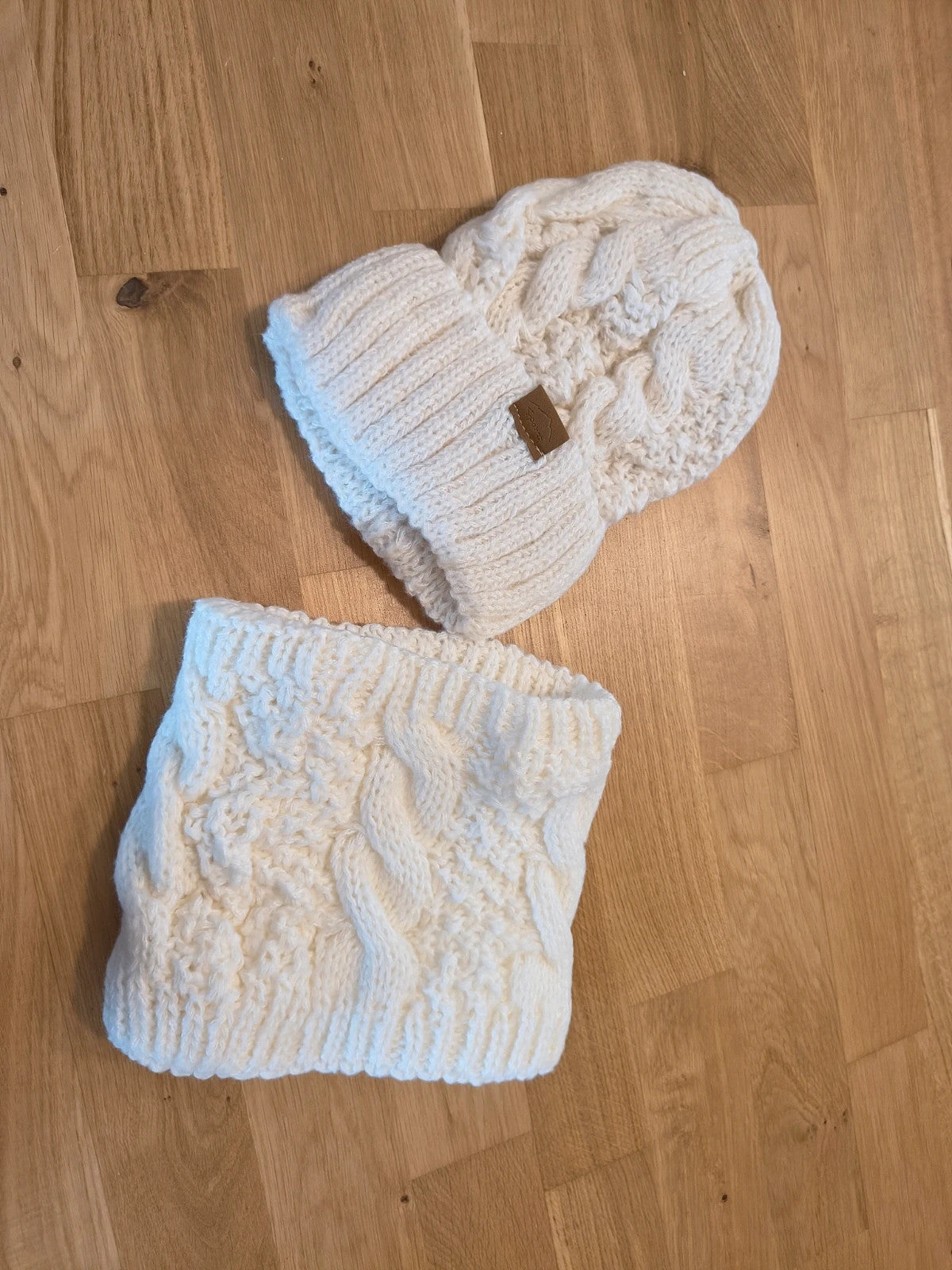 Off-White cream hat and neck warmer set with cable knit pattern, soft polyester material.