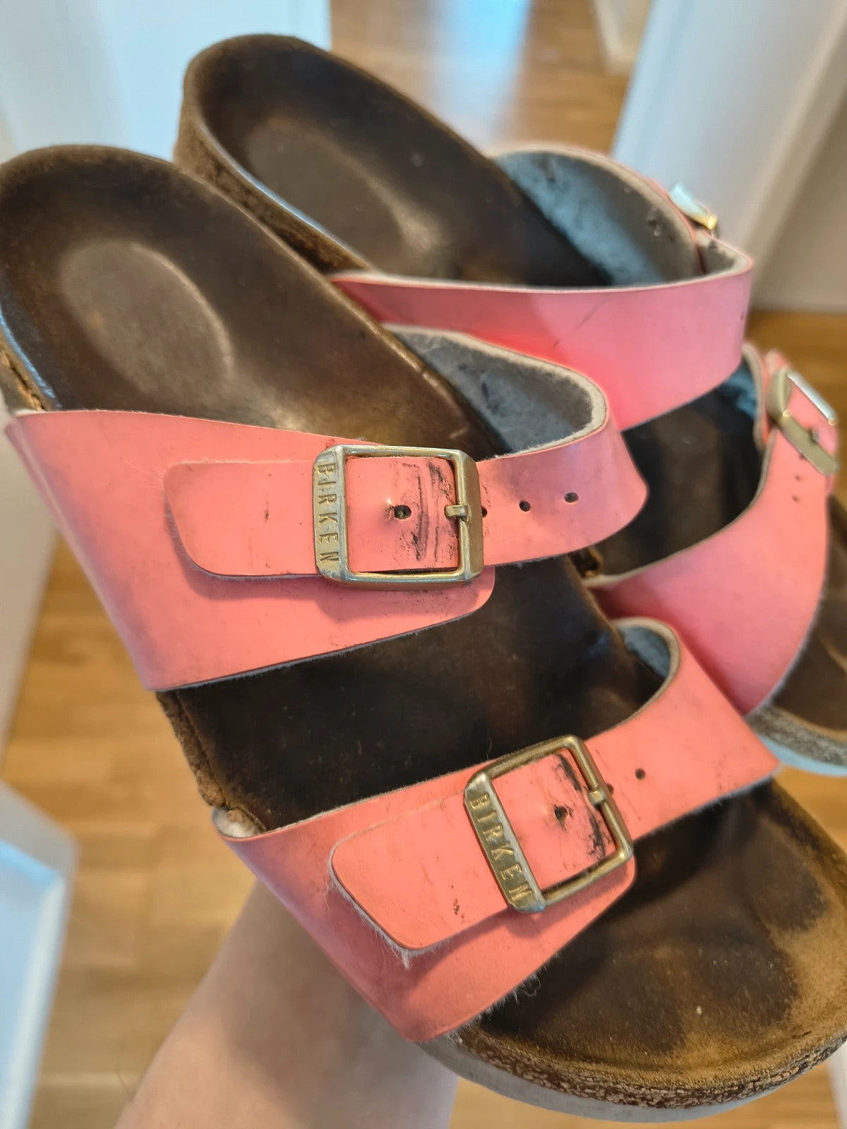 Birkenstock pink deck shoes with two adjustable straps and metal buckles, heavily worn.