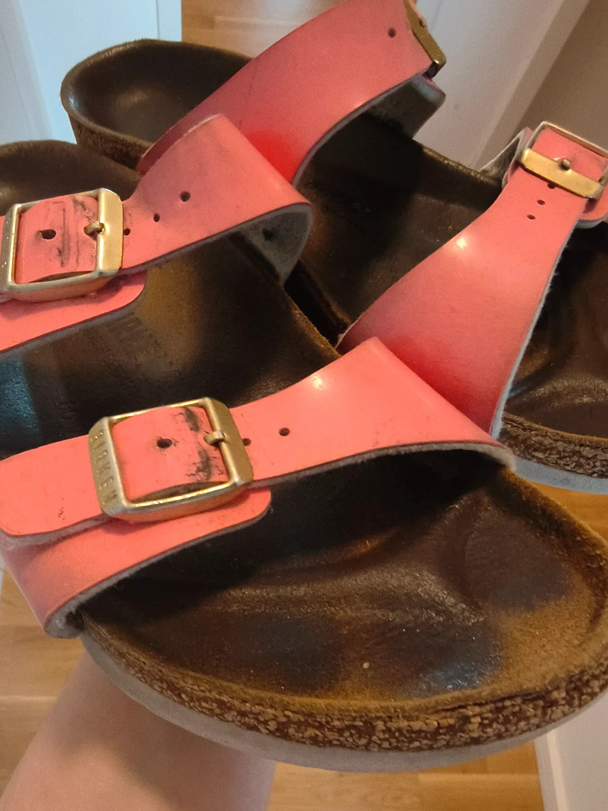 Birkenstock pink deck shoes with two adjustable straps and metal buckles, heavily worn.