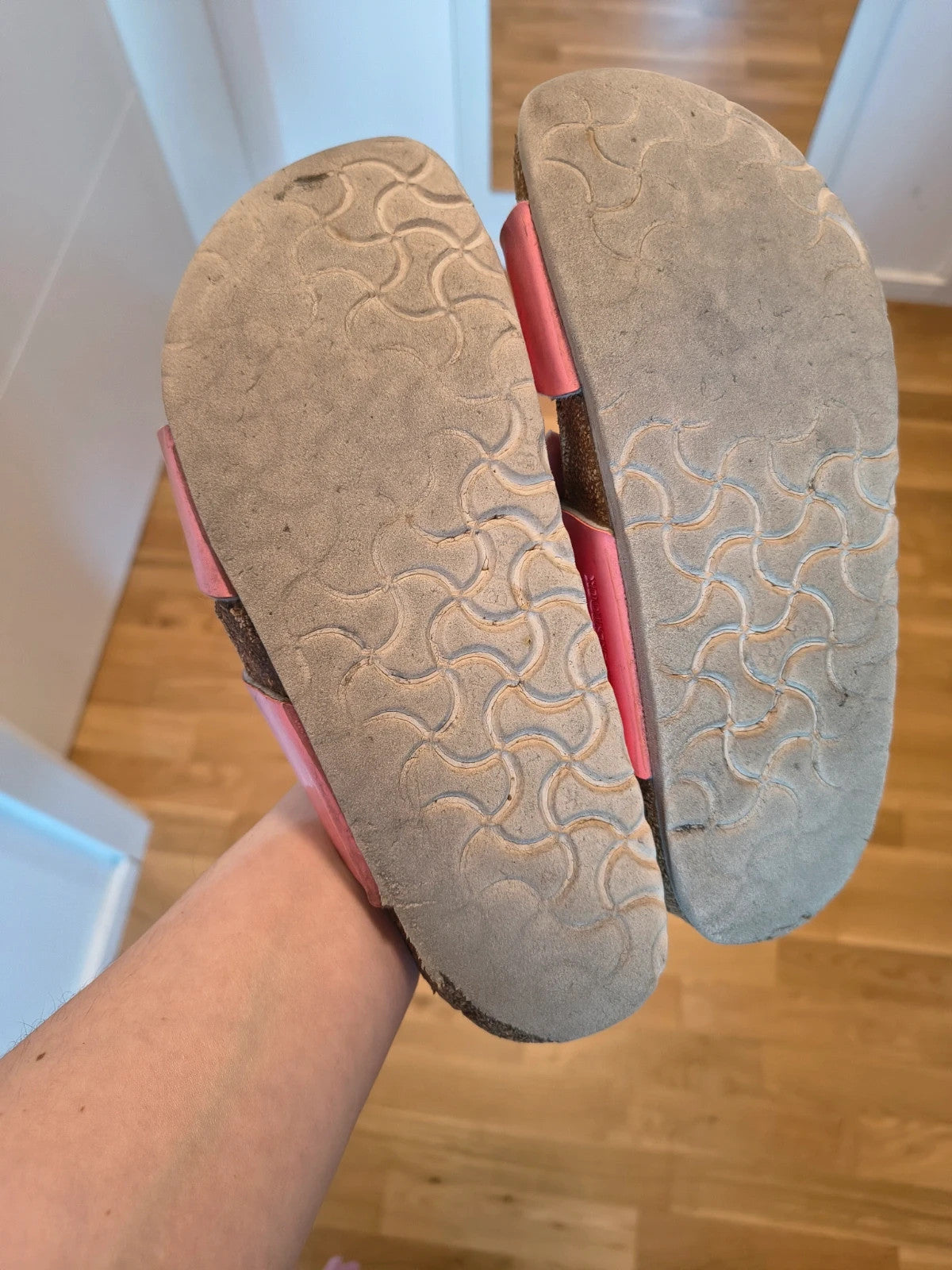 Birkenstock pink deck shoes with two adjustable straps and metal buckles, heavily worn.