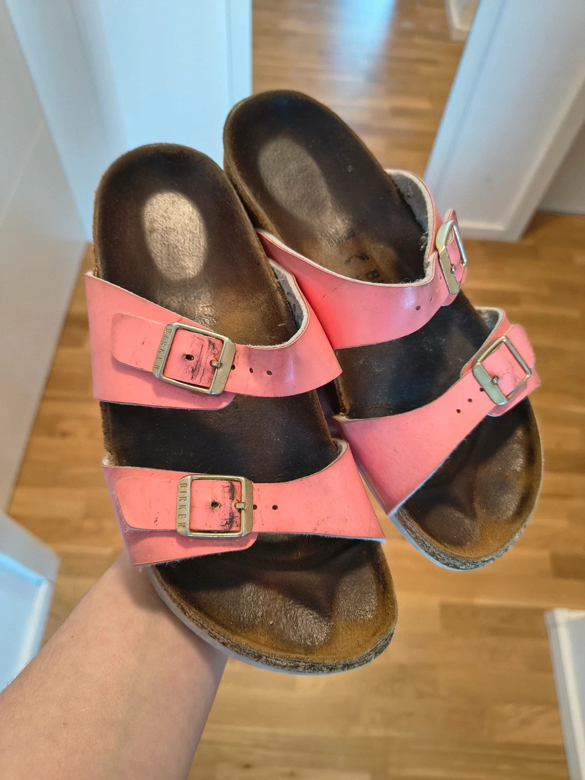 Birkenstock pink deck shoes with two adjustable straps and metal buckles, heavily worn.