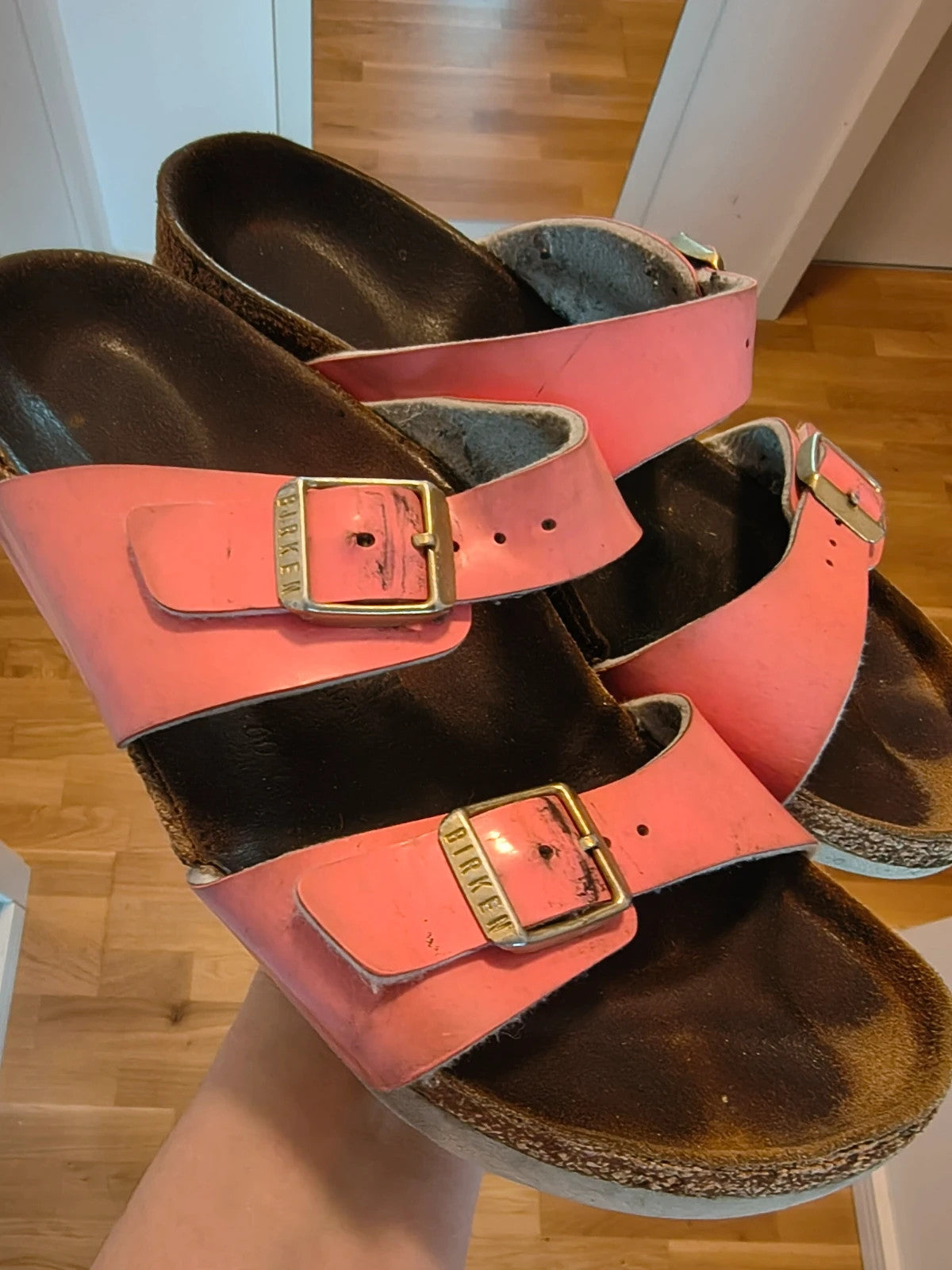 Birkenstock pink deck shoes with two adjustable straps and metal buckles, heavily worn.
