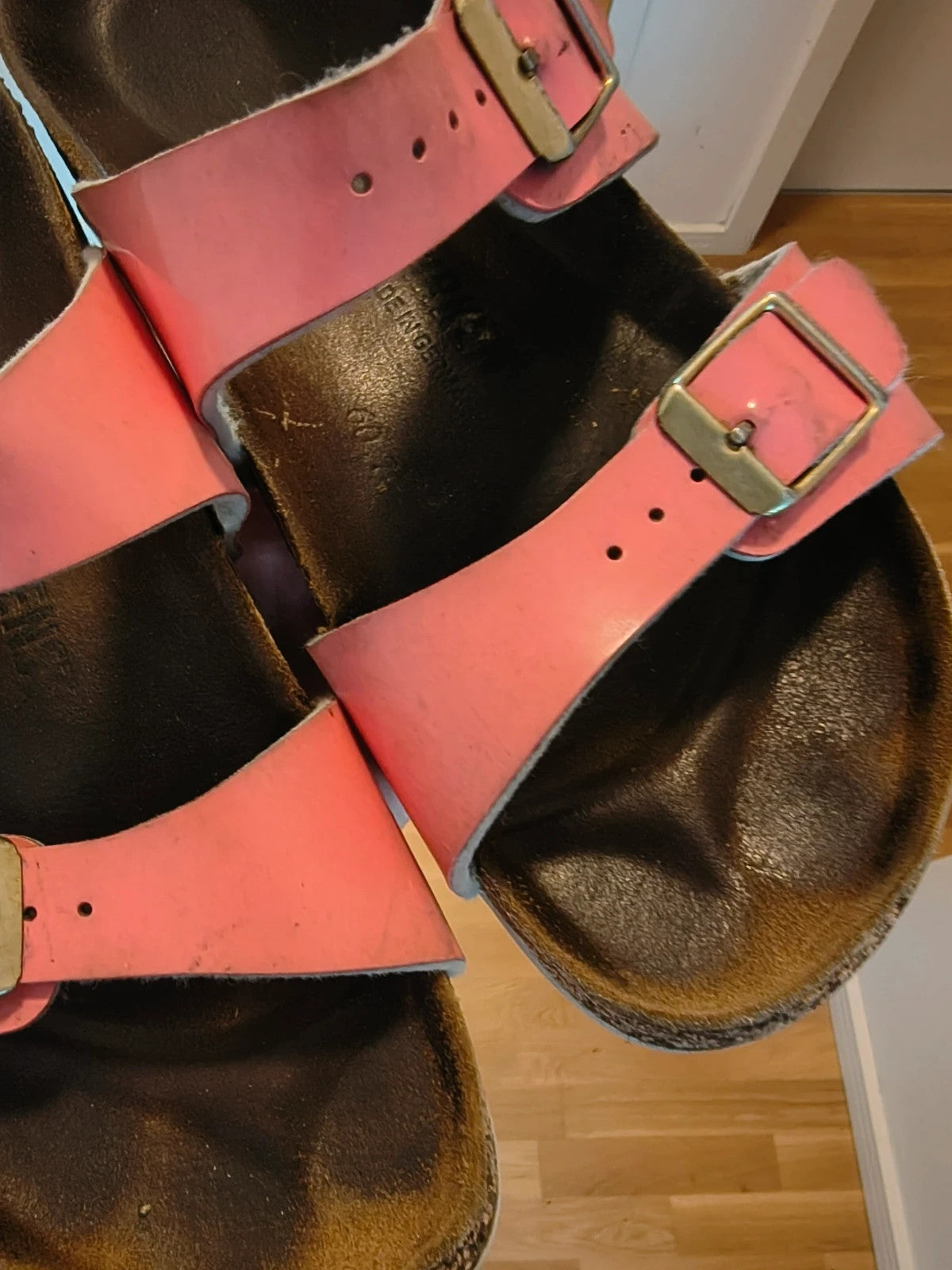 Birkenstock pink deck shoes with two adjustable straps and metal buckles, heavily worn.