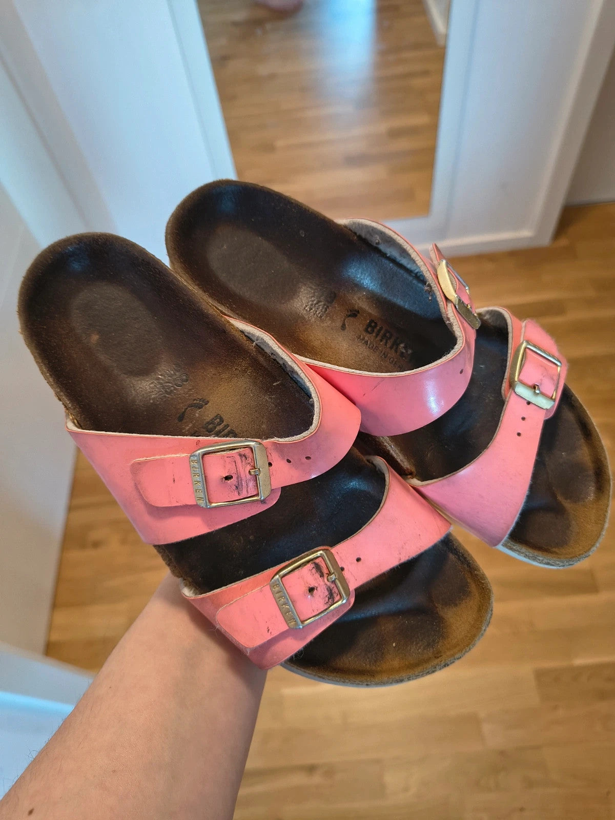 Birkenstock pink deck shoes with two adjustable straps and metal buckles, heavily worn.