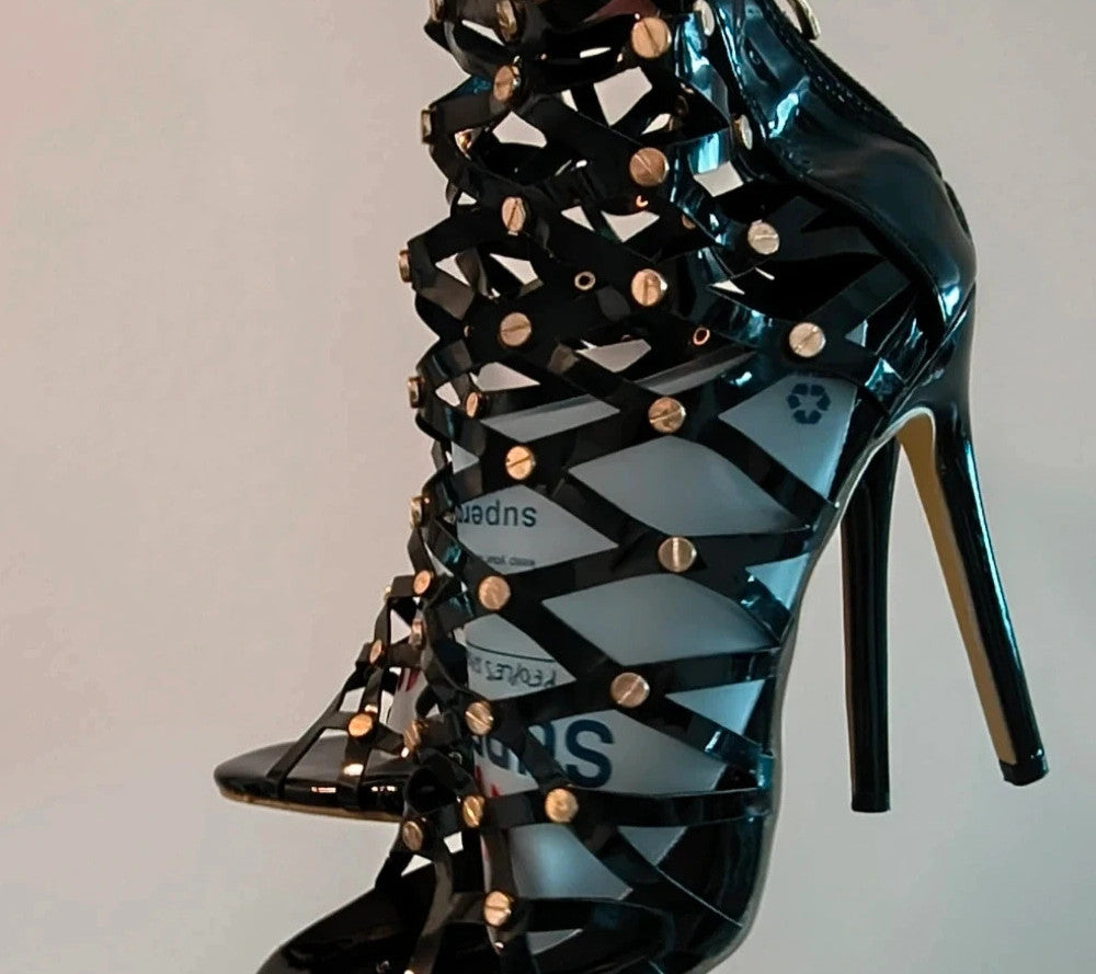 REI black high-heel sandals in patent finish with gold studs and open toe design.