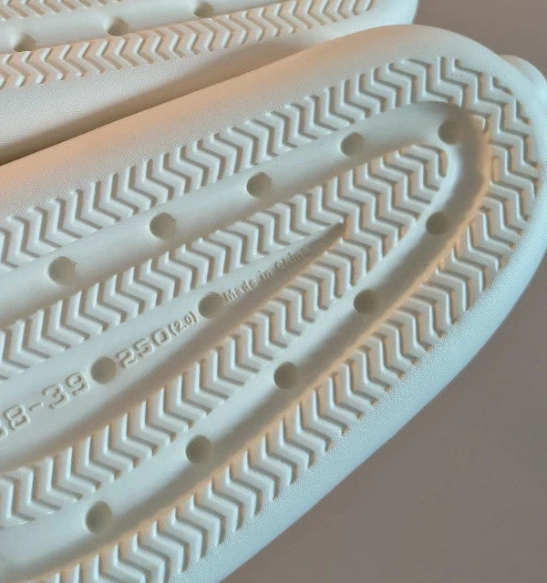 Hasen-Optik cream slides synthetic material with textured design and logo detail.