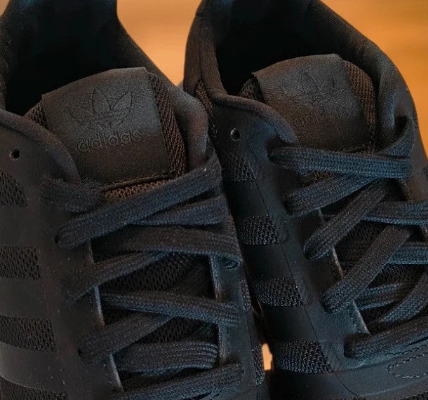 Adidas black trainers with synthetic and textile material, classic design, original box included.