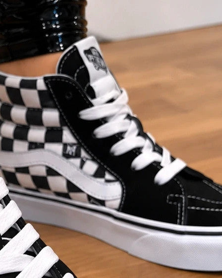 VANS black and white checkerboard high-top trainers with classic side stripe and leather material.
