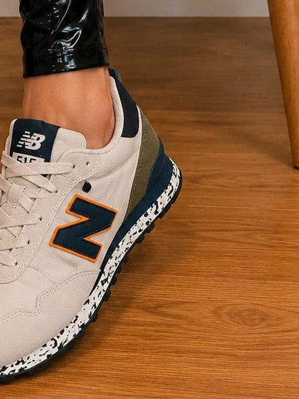 New Balance beige trainers with dark accents, textile and synthetic materials.
