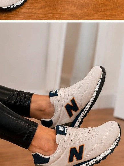 New Balance beige trainers with dark accents, textile and synthetic materials.