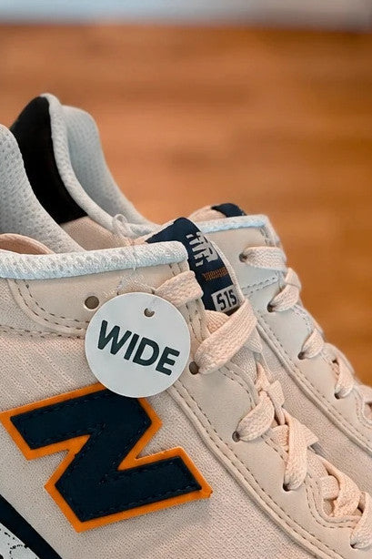New Balance beige trainers with dark accents, textile and synthetic materials.