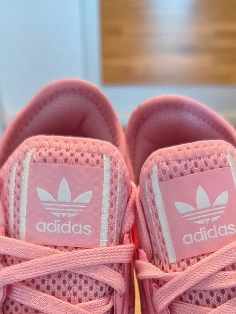 Adidas pink and white trainers with synthetic and textile materials, featuring slip-on and lace-up design.