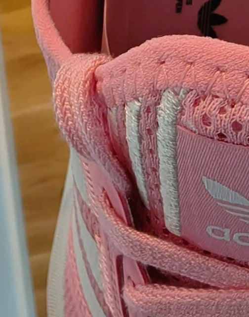 Adidas pink and white trainers with synthetic and textile materials, featuring slip-on and lace-up design.
