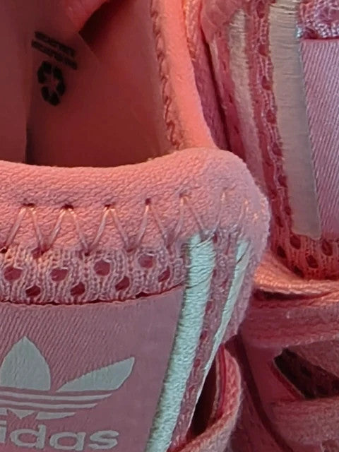 Adidas pink and white trainers with synthetic and textile materials, featuring slip-on and lace-up design.