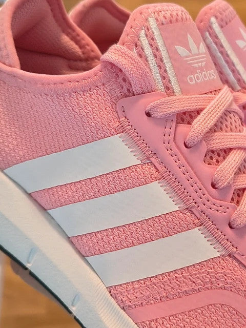 Adidas pink and white trainers with synthetic and textile materials, featuring slip-on and lace-up design.