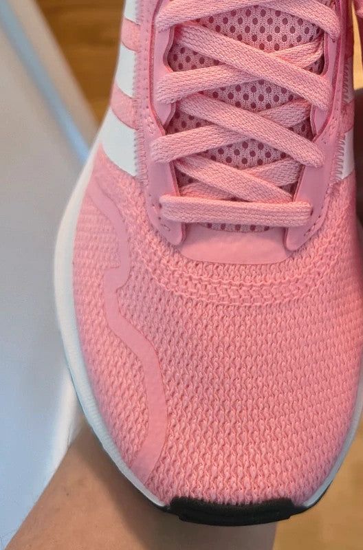 Adidas pink and white trainers with synthetic and textile materials, featuring slip-on and lace-up design.