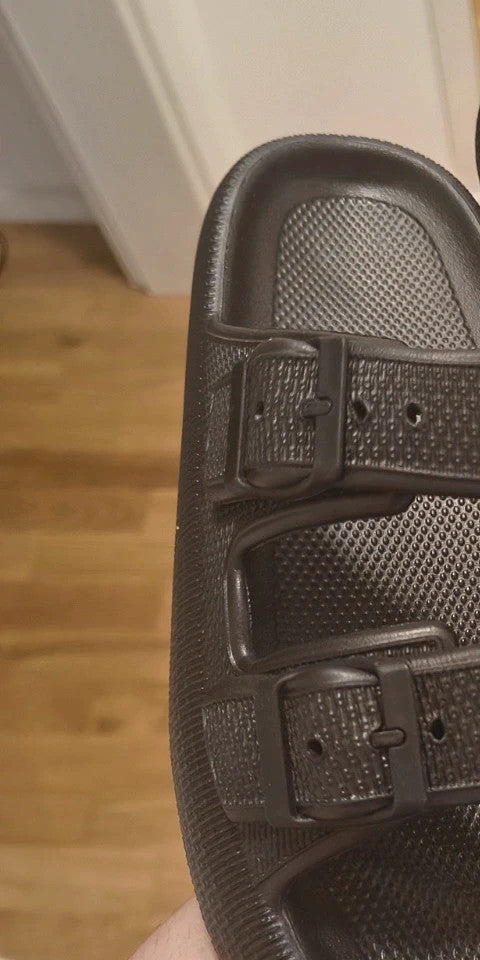 Schwarze Slipper mit zwei verstellbaren Schnallen, leichtes Synthetikmaterial, strukturierte Innensohle.